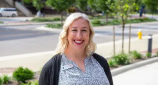 Brittney smiling in a patterned shirt and a cardigan