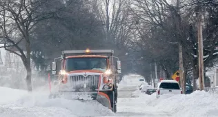 A snowplow clears the road on an Akron street
