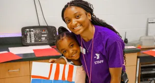 Staff member with a camper, holding a craft
