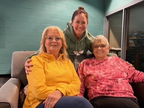 Three women smiling at the camera on a couch