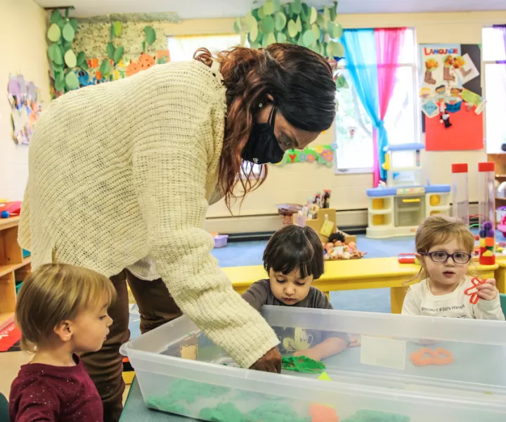 Teacher leaning over toddler