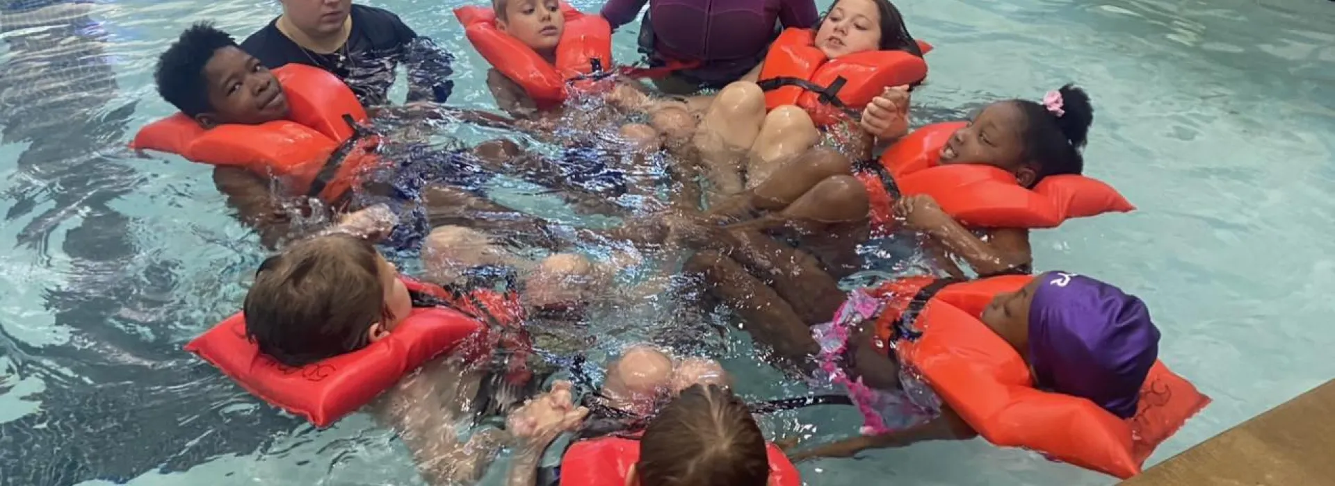 Group of kids in lifejackets learning how to swim