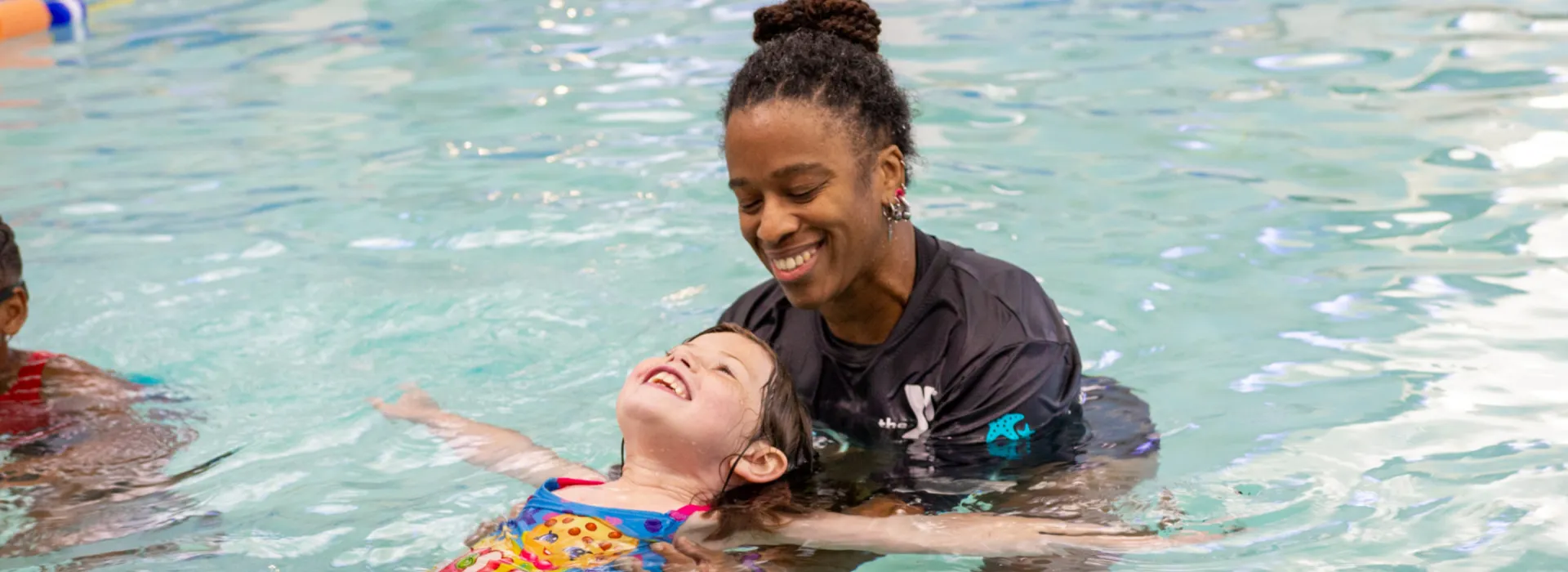 Swim instructor helping a student float