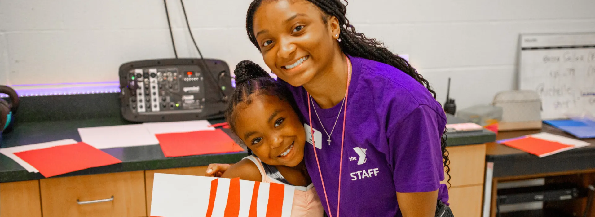 Staff member with a camper, holding a craft