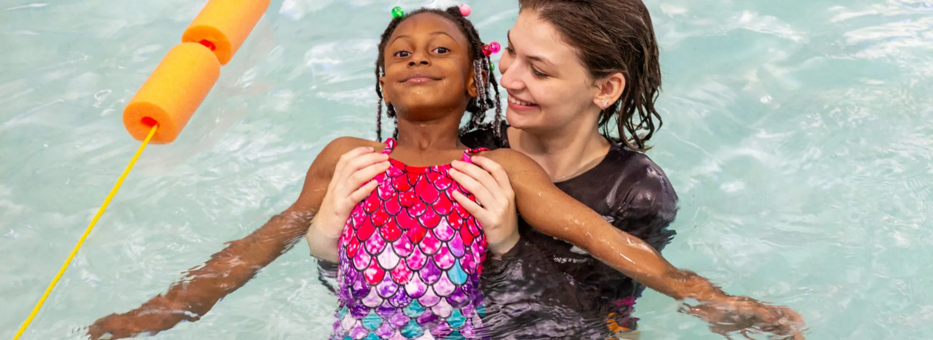 Swim instructor helping a student float